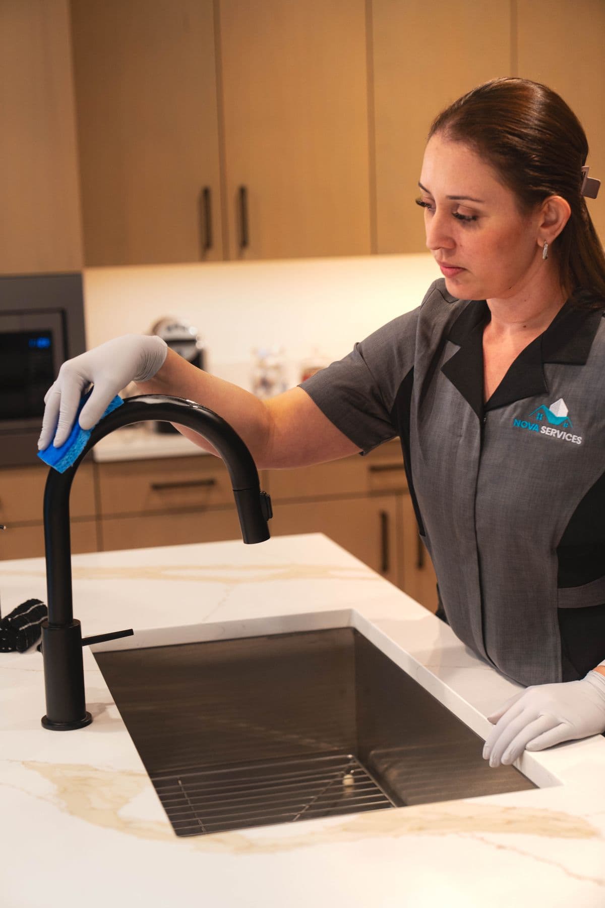 Nova cleaner polishing a black kitchen faucet and sink